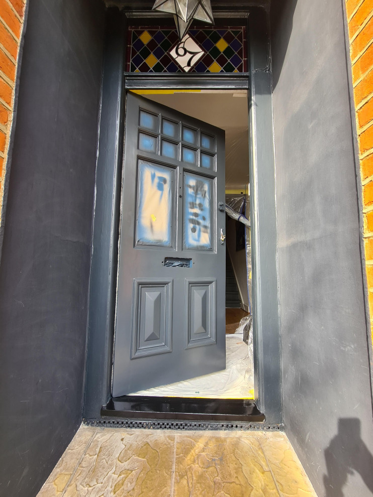 Inspiration for a medium sized traditional front door in London with black walls, dark hardwood flooring, a single front door, a black front door, brown floors and a drop ceiling.