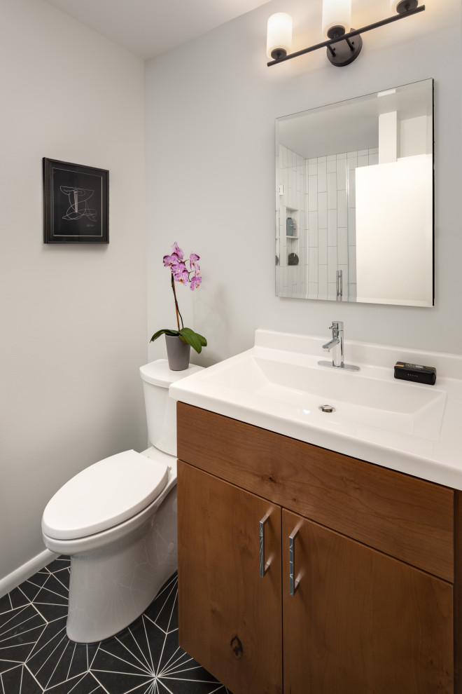 Exemple d'une petite salle de bain moderne en bois brun avec un placard à porte plane, WC séparés, un carrelage blanc, des carreaux de céramique, un mur gris, un sol en carrelage de céramique, un lavabo intégré, un plan de toilette en surface solide, un sol noir, une cabine de douche à porte battante, un plan de toilette blanc, une niche, meuble simple vasque et meuble-lavabo encastré.