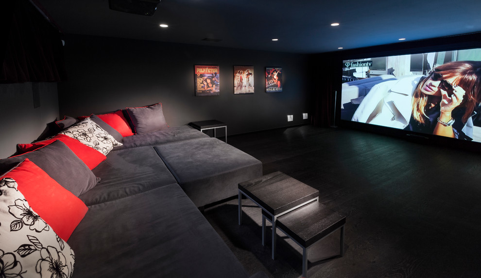 This is an example of a large modern enclosed home theatre in Tel Aviv with black walls, dark hardwood floors, a built-in media wall and black floor.