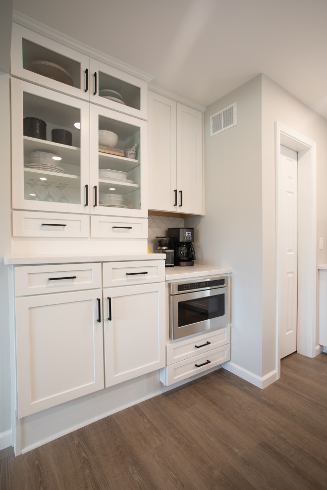Inspiration for a transitional vinyl floor kitchen remodel with shaker cabinets, white cabinets, quartz countertops, white backsplash, porcelain backsplash, stainless steel appliances and white countertops
