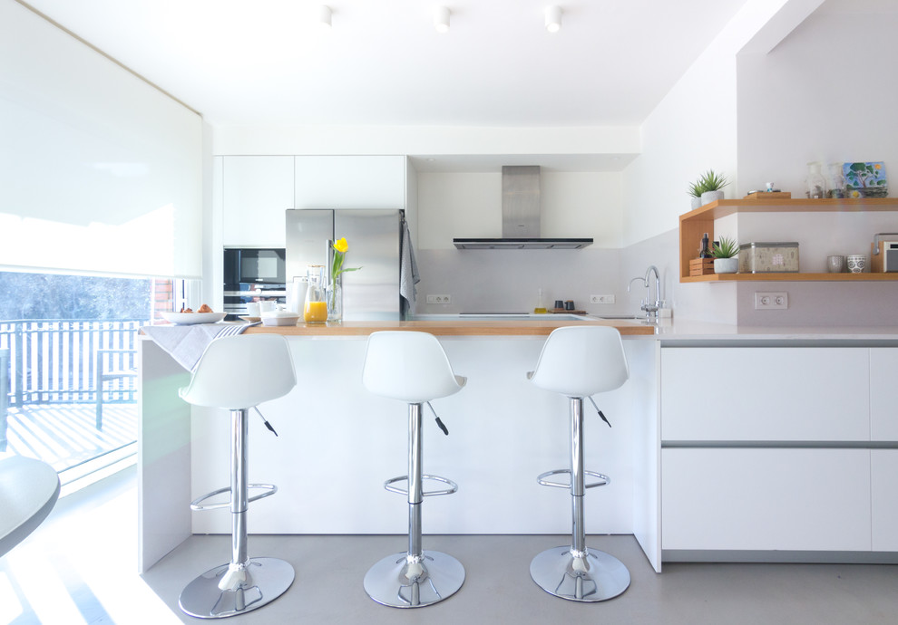 Inspiration for a mid-sized contemporary u-shaped open plan kitchen in Barcelona with flat-panel cabinets, white cabinets, grey splashback, stainless steel appliances, a peninsula, grey floor, wood benchtops and beige benchtop.