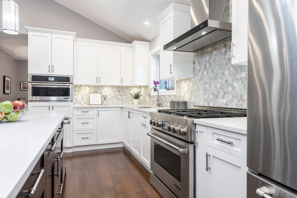 Large transitional l-shaped medium tone wood floor and brown floor eat-in kitchen photo in Vancouver with an undermount sink, shaker cabinets, white cabinets, quartzite countertops, multicolored backsplash, marble backsplash, stainless steel appliances, an island and white countertops