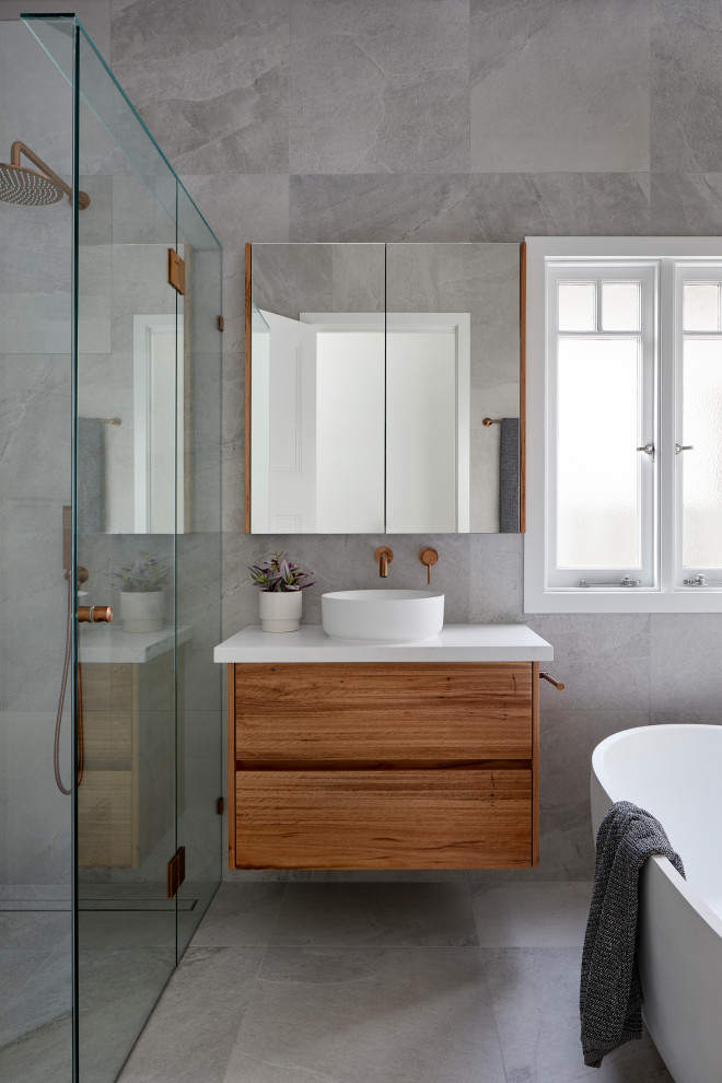 Photo of a small contemporary master bathroom in Melbourne with white cabinets, a freestanding tub, a corner shower, a wall-mount toilet, gray tile, porcelain tile, white walls, porcelain floors, engineered quartz benchtops, grey floor, a hinged shower door, white benchtops, a niche and a single vanity.