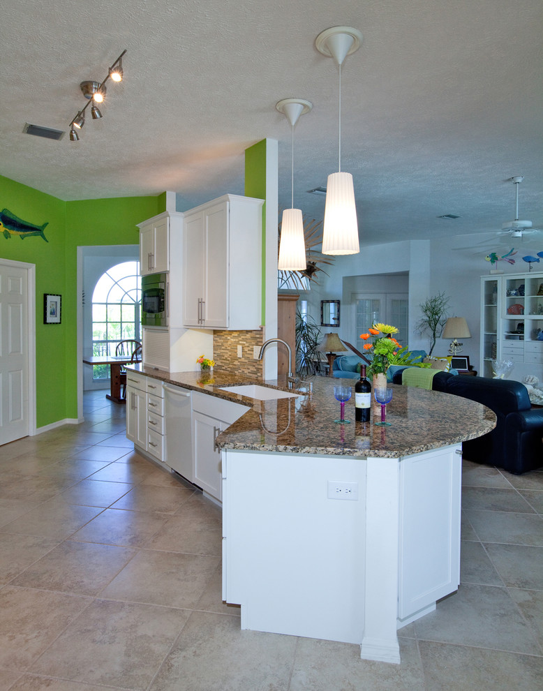 Photo of a mid-sized beach style galley eat-in kitchen in Tampa with an undermount sink, shaker cabinets, white cabinets, granite benchtops, brown splashback, white appliances and ceramic floors.