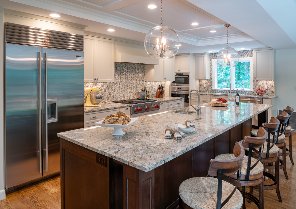 Example of a kitchen design in Boston with white cabinets, mosaic tile backsplash, stainless steel appliances and an island