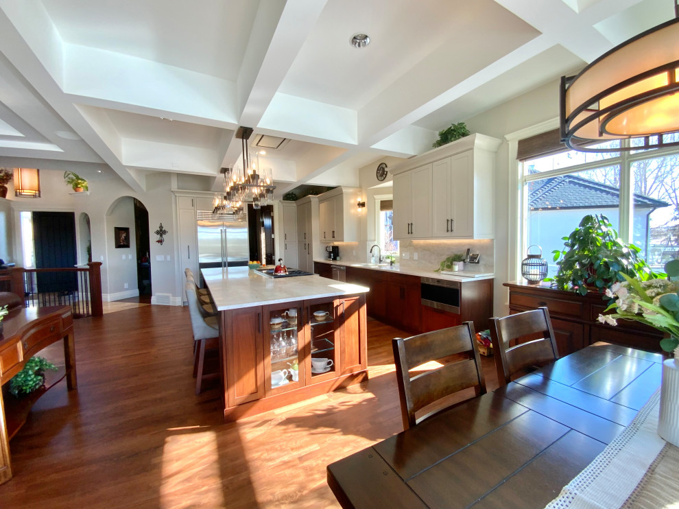 Inspiration for a large transitional single-wall dark wood floor, brown floor and coffered ceiling eat-in kitchen remodel in Calgary with an undermount sink, shaker cabinets, gray cabinets, quartzite countertops, white backsplash, stainless steel appliances, an island and white countertops