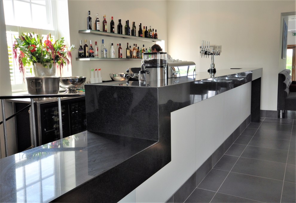 Inspiration for a large contemporary home bar in Essex with porcelain floors, grey floor and black benchtop.