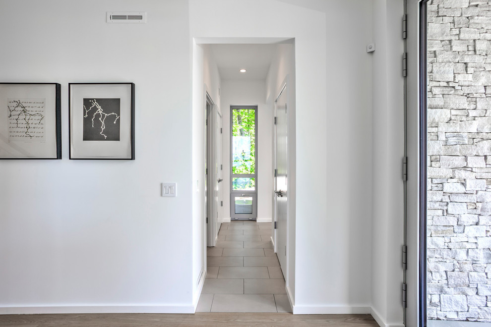 Design ideas for a mid-sized modern hallway in New York with white walls, porcelain floors and grey floor.