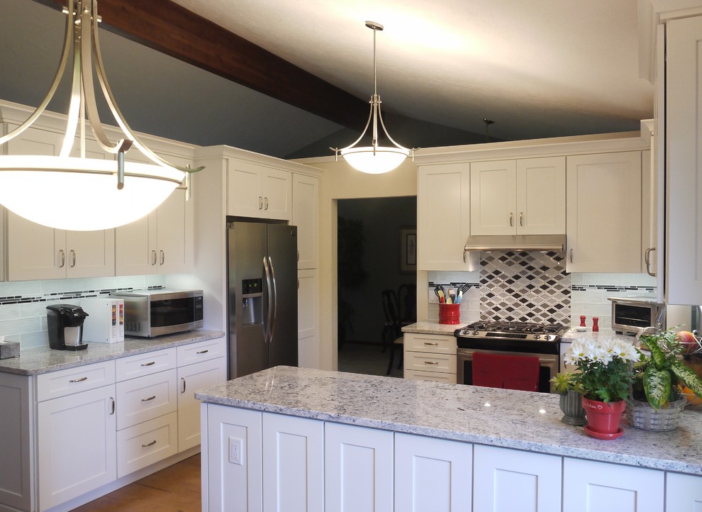 Design ideas for a mid-sized transitional u-shaped eat-in kitchen in Grand Rapids with shaker cabinets, white cabinets, granite benchtops, multi-coloured splashback, glass tile splashback, stainless steel appliances, medium hardwood floors, a peninsula and a double-bowl sink.