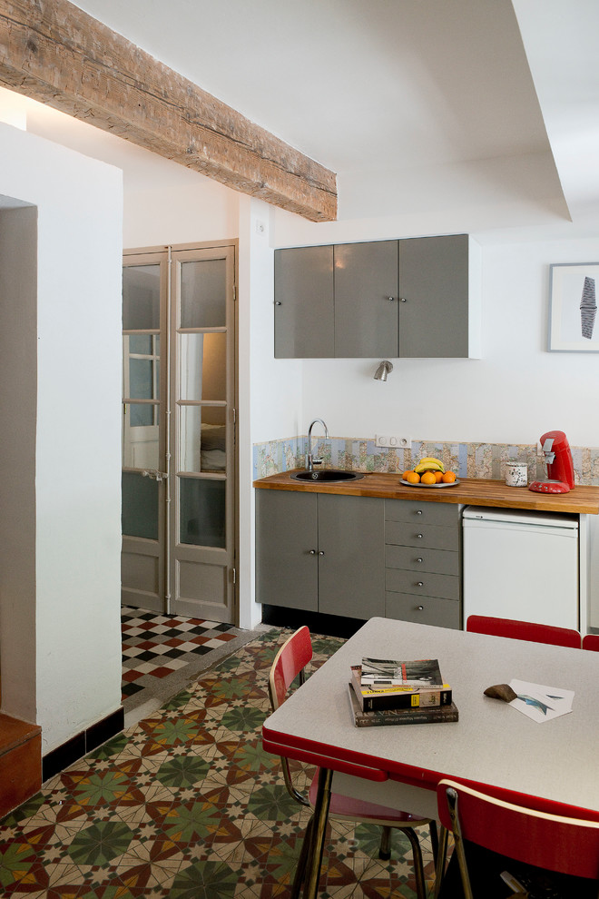 This is an example of a mid-sized country single-wall eat-in kitchen in Montpellier with grey cabinets, no island and wood benchtops.