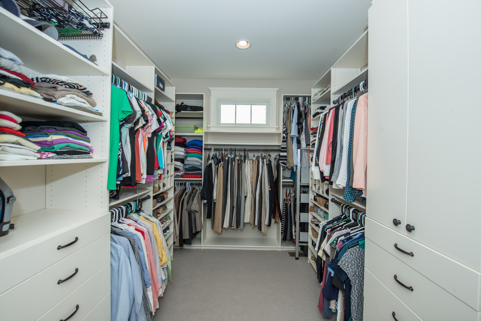 This is an example of a large traditional gender-neutral walk-in wardrobe in Other with open cabinets, white cabinets, carpet and grey floor.