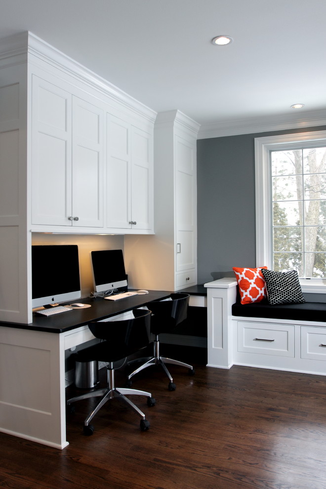 This is an example of a mid-sized traditional study room in Milwaukee with grey walls, dark hardwood floors, no fireplace and a built-in desk.