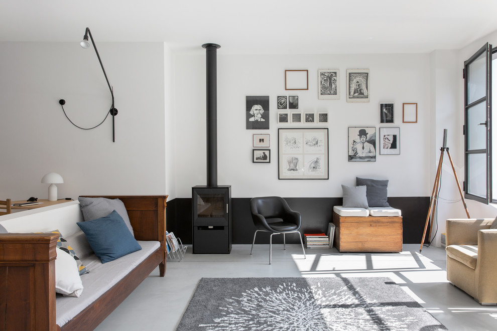 Photo of an expansive industrial open concept living room in Milan with white walls, concrete floors, a wood stove, a metal fireplace surround, no tv and grey floor.