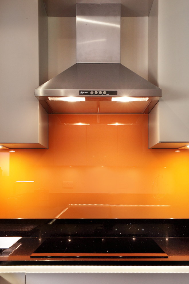 Inspiration for a mid-sized contemporary u-shaped eat-in kitchen in Buckinghamshire with flat-panel cabinets, grey cabinets, quartzite benchtops, orange splashback, glass sheet splashback, stainless steel appliances, terra-cotta floors, a peninsula and an undermount sink.