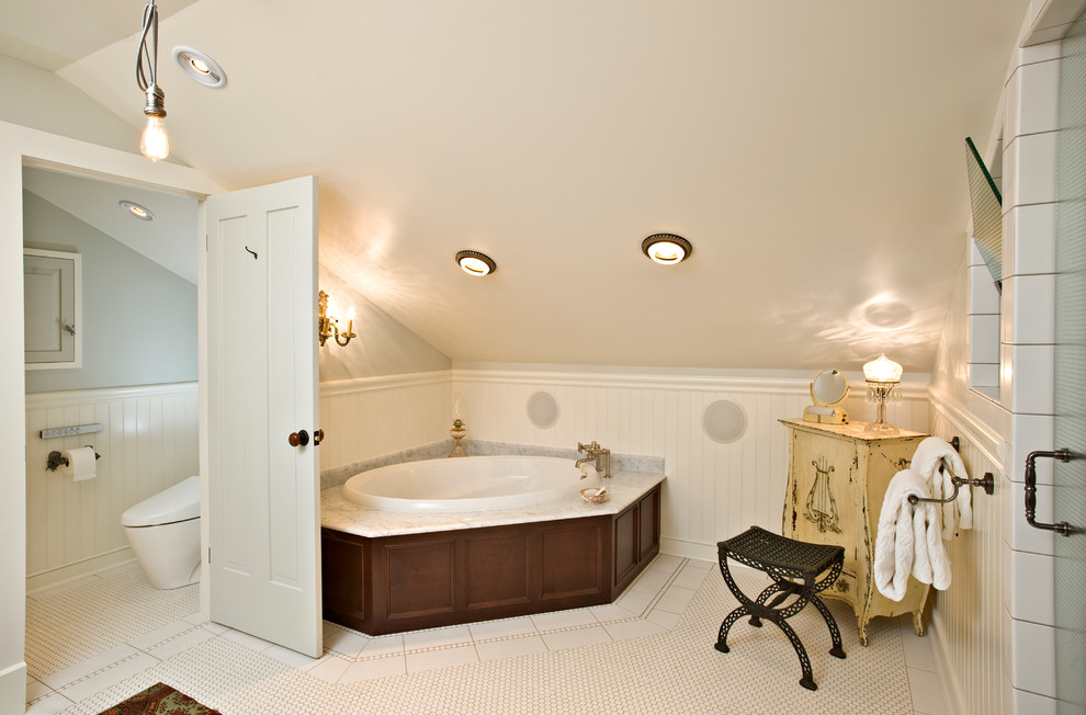 This is an example of a traditional bathroom in Columbus with a drop-in tub and beige tile.
