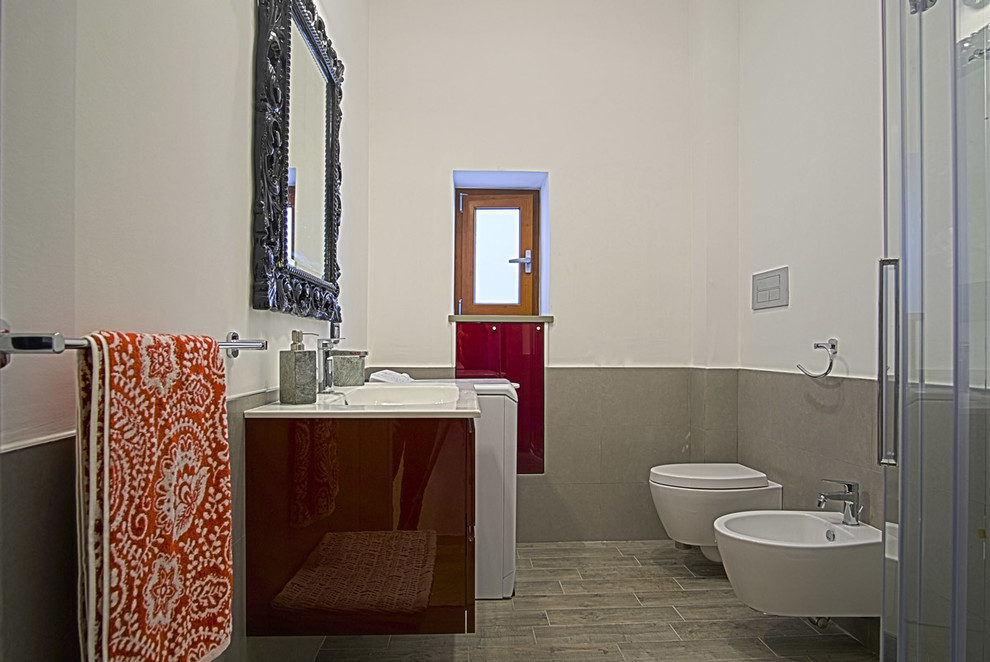 Photo of an asian 3/4 bathroom in Other with beaded inset cabinets, red cabinets, a corner shower, a wall-mount toilet, gray tile, porcelain tile, white walls, porcelain floors, an integrated sink, engineered quartz benchtops, grey floor and a sliding shower screen.