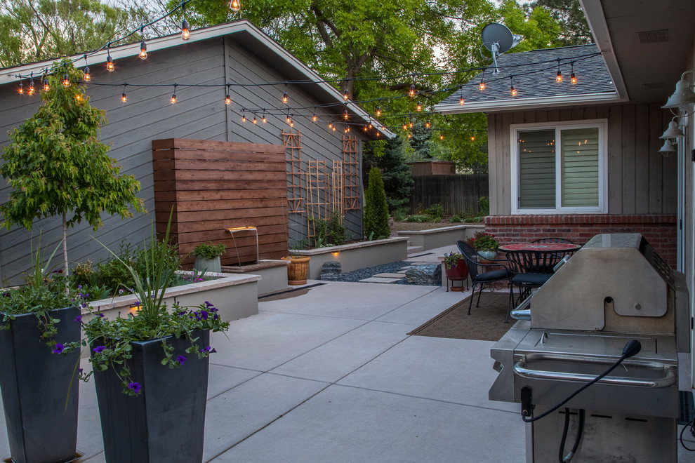 This is an example of a small modern backyard partial sun formal garden in Denver with a water feature and natural stone pavers.