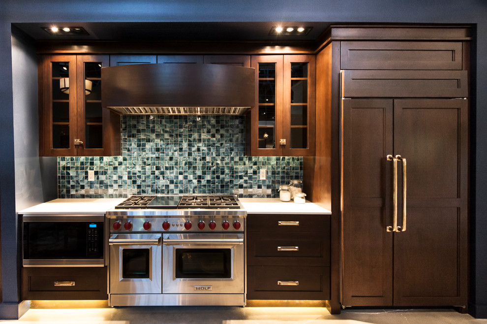 This is an example of a small arts and crafts single-wall separate kitchen in Salt Lake City with stainless steel appliances, concrete floors, no island, glass-front cabinets, dark wood cabinets, quartzite benchtops, blue splashback and glass tile splashback.