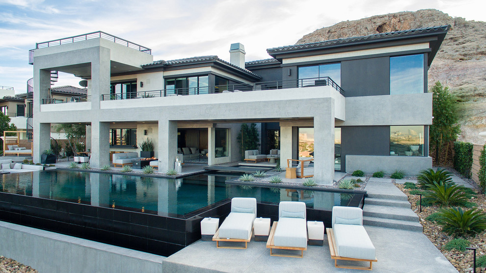 Large trendy backyard concrete paver and rectangular infinity pool fountain photo in Las Vegas