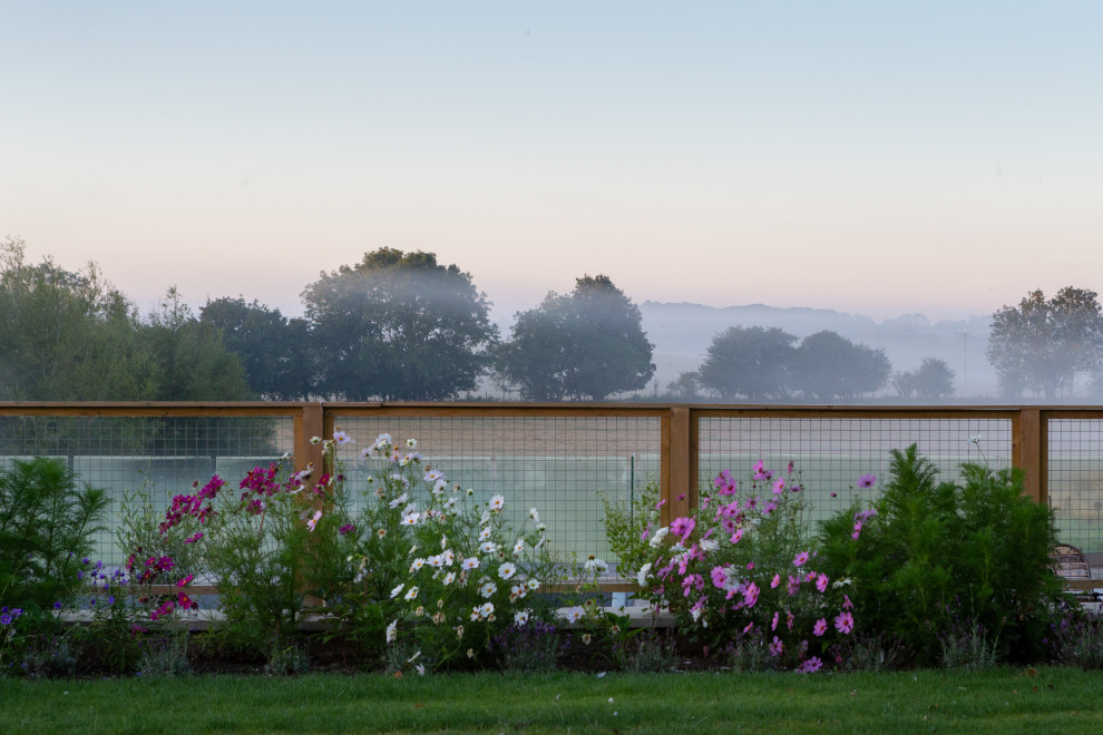 Foto di un grande giardino country esposto in pieno sole dietro casa in estate con pavimentazioni in pietra naturale e recinzione in pietra