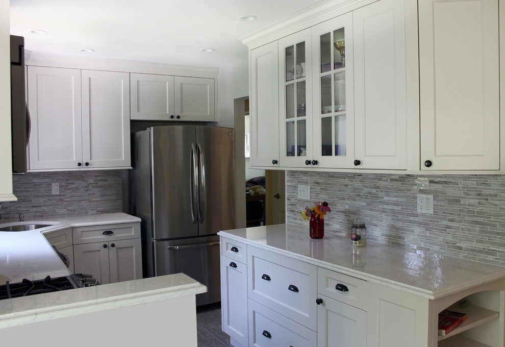 Enclosed kitchen - mid-sized transitional galley light wood floor and brown floor enclosed kitchen idea in New York with an undermount sink, recessed-panel cabinets, white cabinets, marble countertops, beige backsplash, matchstick tile backsplash, stainless steel appliances and no island