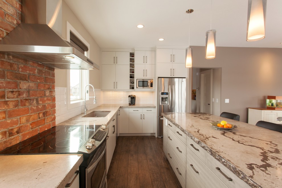 Photo of a mid-sized modern l-shaped eat-in kitchen in Calgary with an undermount sink, flat-panel cabinets, white cabinets, concrete benchtops, white splashback, subway tile splashback, stainless steel appliances, medium hardwood floors and with island.