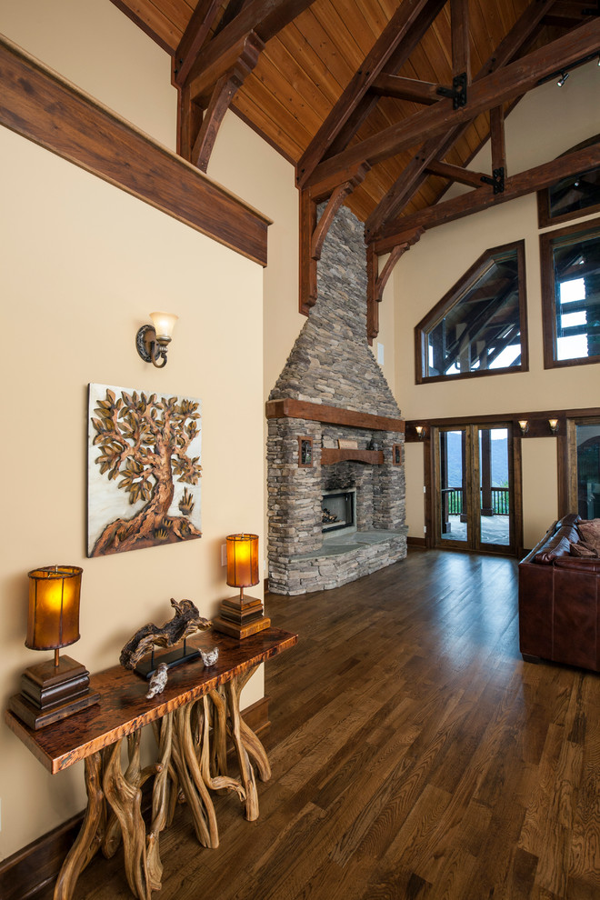Inspiration for an expansive country open concept living room in Charlotte with beige walls, medium hardwood floors, a two-sided fireplace, a stone fireplace surround and a concealed tv.