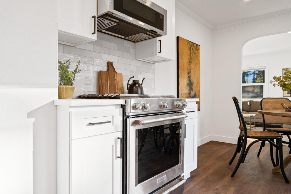 Transitional galley dark wood floor and brown floor eat-in kitchen photo in Seattle with an undermount sink, shaker cabinets, white cabinets, quartzite countertops, gray backsplash, ceramic backsplash, stainless steel appliances, no island and white countertops