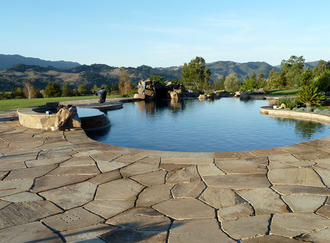 Photo of a large mediterranean backyard custom-shaped pool in San Luis Obispo with natural stone pavers.