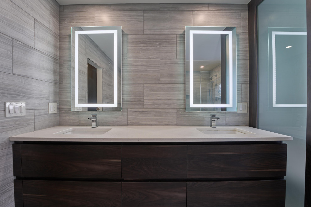 Photo of a mid-sized modern master bathroom in Philadelphia with flat-panel cabinets, gray tile, grey walls, grey floor, a hinged shower door, white benchtops, a shower seat, a double vanity, grey cabinets, a two-piece toilet, ceramic tile, linoleum floors, a drop-in sink, limestone benchtops and a built-in vanity.