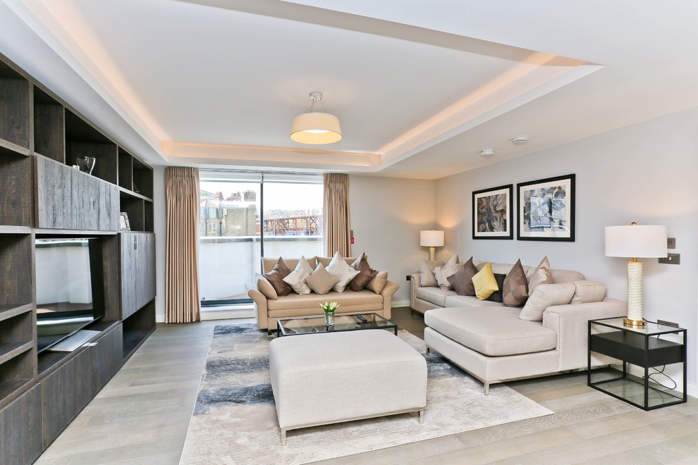 Transitional living room in London with white walls, light hardwood floors, a freestanding tv and beige floor.