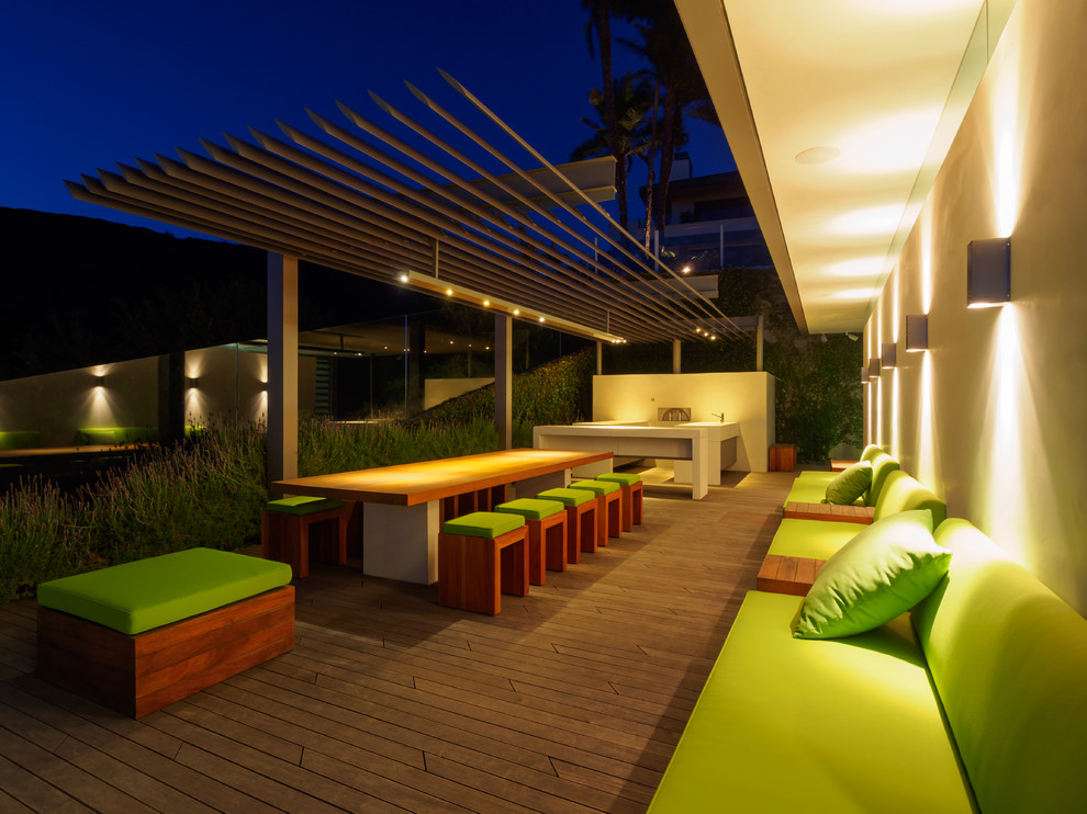 This is an example of a large contemporary backyard deck in Orange County with an outdoor kitchen and a pergola.