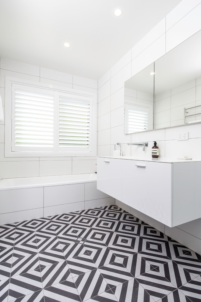 Photo of a mid-sized contemporary master bathroom in Brisbane with flat-panel cabinets, white cabinets, a drop-in tub, a corner shower, a one-piece toilet, black and white tile, porcelain tile, yellow walls, porcelain floors, an integrated sink and solid surface benchtops.