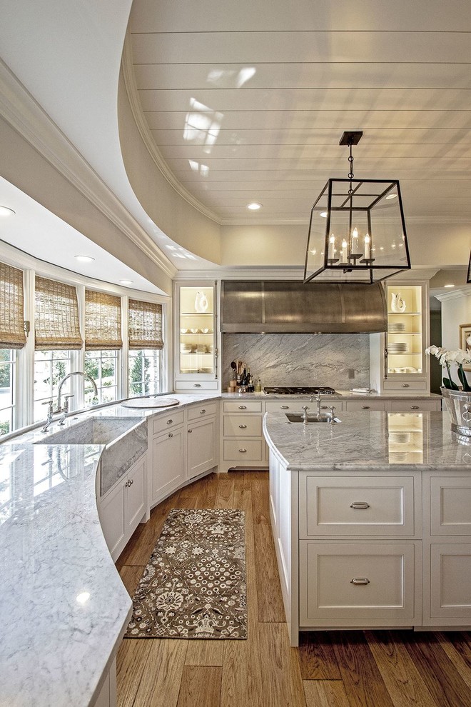 Inspiration for a large transitional l-shaped open plan kitchen in Austin with a farmhouse sink, shaker cabinets, white cabinets, marble benchtops, multi-coloured splashback, stone slab splashback, stainless steel appliances, medium hardwood floors and with island.