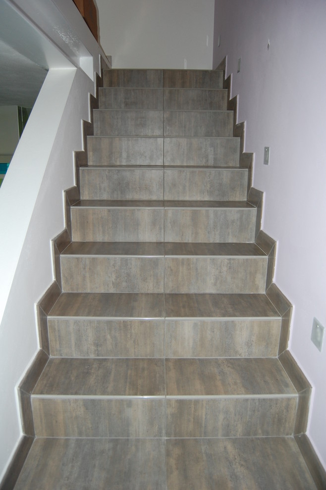 Design ideas for a small transitional tile straight staircase in Milan with tile risers.