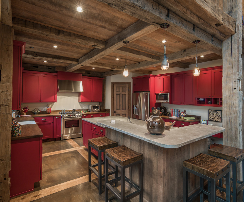 This is an example of a country u-shaped kitchen in Charleston with a farmhouse sink, shaker cabinets, red cabinets, stainless steel appliances and concrete benchtops.