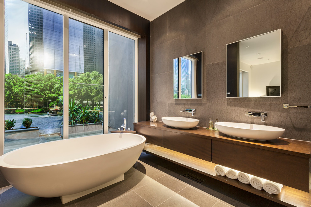 Photo of a mid-sized contemporary master bathroom in Melbourne with flat-panel cabinets, dark wood cabinets, a freestanding tub, brown tile, a vessel sink, brown floor, wood benchtops and brown benchtops.