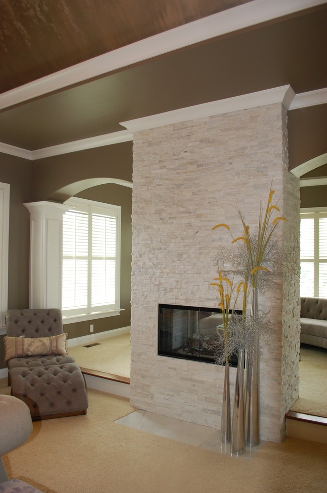 Inspiration for a mid-sized traditional master bedroom in Indianapolis with beige walls, carpet, a two-sided fireplace and a stone fireplace surround.
