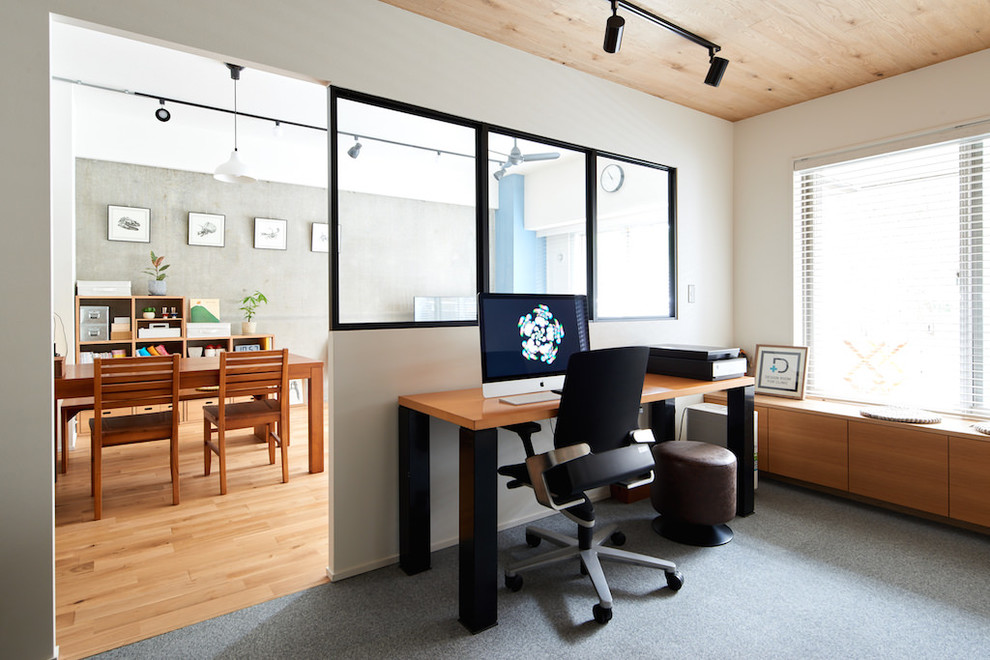 This is an example of an industrial home office in Other with white walls, carpet, a freestanding desk and grey floor.