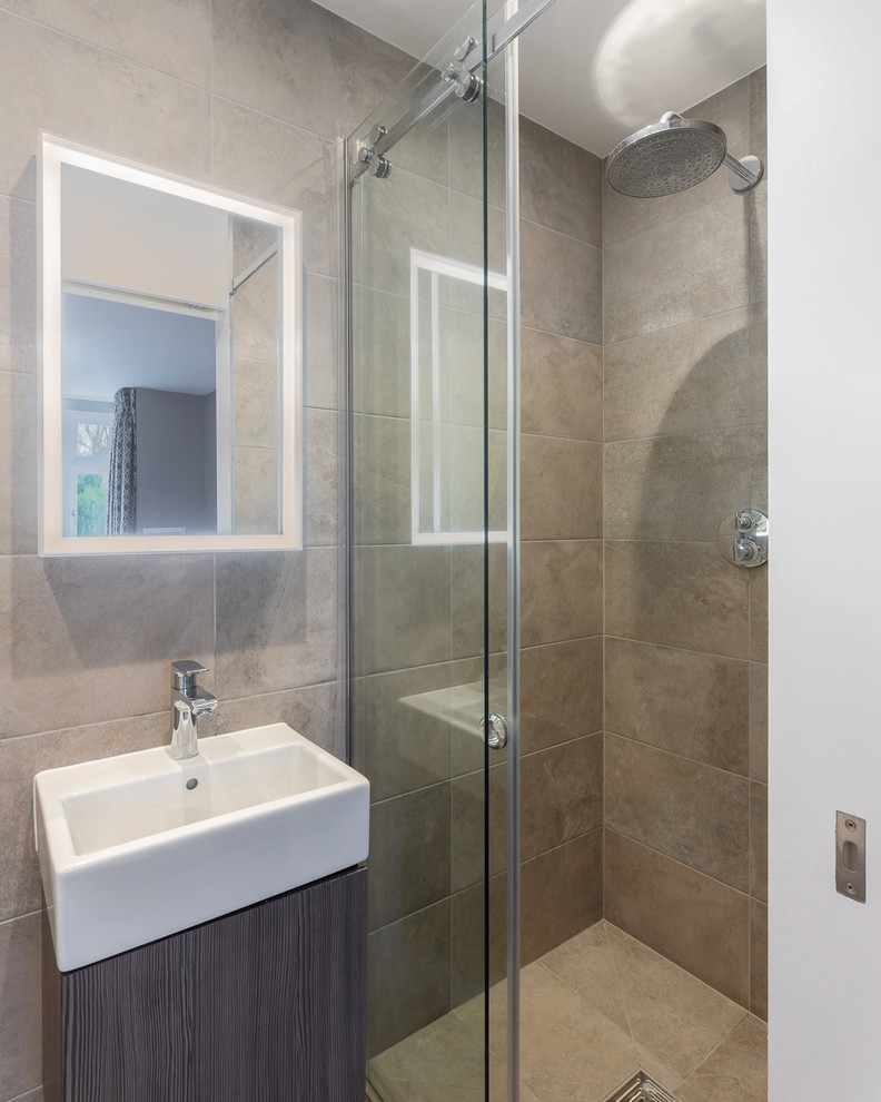 This is an example of a small transitional 3/4 bathroom in Hertfordshire with glass-front cabinets, white cabinets, an open shower, a wall-mount toilet, brown tile, ceramic tile, brown walls, ceramic floors, a wall-mount sink, brown floor and a sliding shower screen.