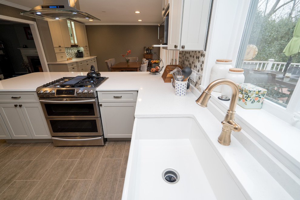 Inspiration for a mid-sized transitional l-shaped laminate floor open concept kitchen remodel in DC Metro with a farmhouse sink, shaker cabinets, white cabinets, quartz countertops, gray backsplash, porcelain backsplash, stainless steel appliances and a peninsula