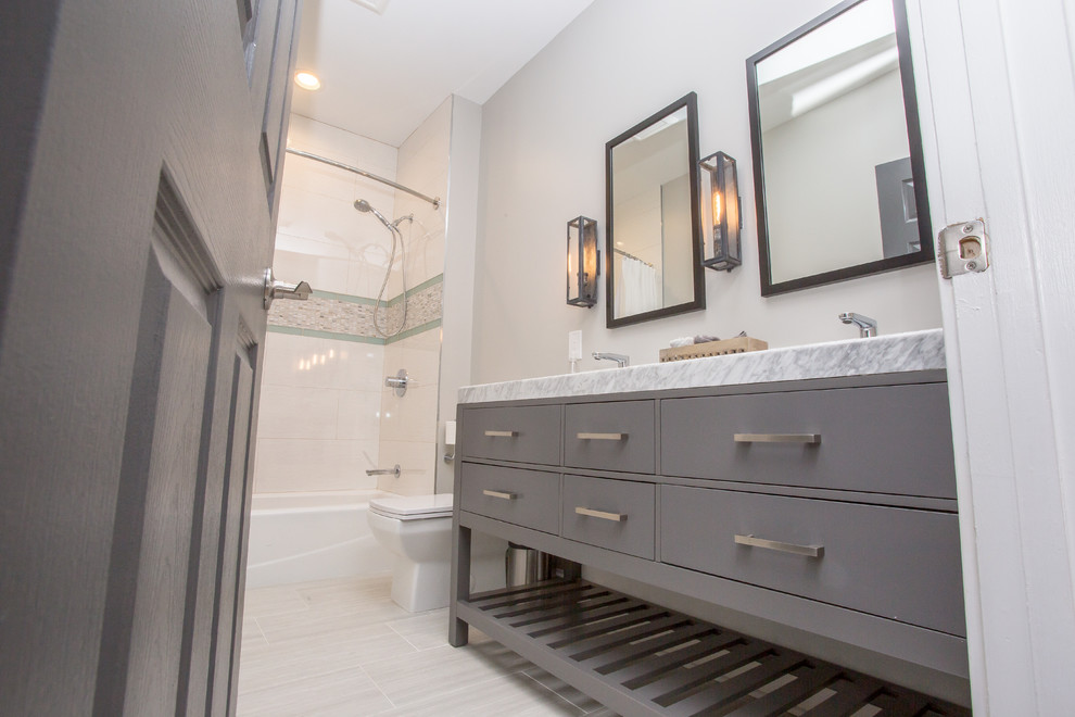 Inspiration for a mid-sized contemporary kids bathroom in DC Metro with shaker cabinets, grey cabinets, a shower/bathtub combo, a one-piece toilet, white tile, glass tile, white walls, porcelain floors, an undermount sink, marble benchtops, white floor, a shower curtain and white benchtops.