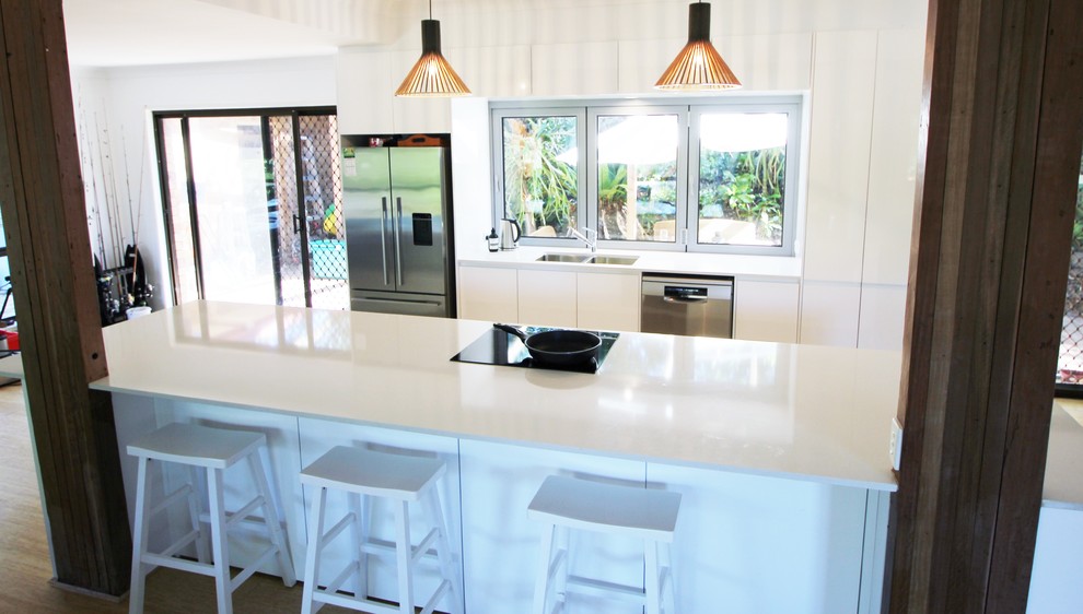 Photo of a mid-sized beach style galley eat-in kitchen in Sunshine Coast with an undermount sink, white cabinets, quartz benchtops, stainless steel appliances, with island and white benchtop.