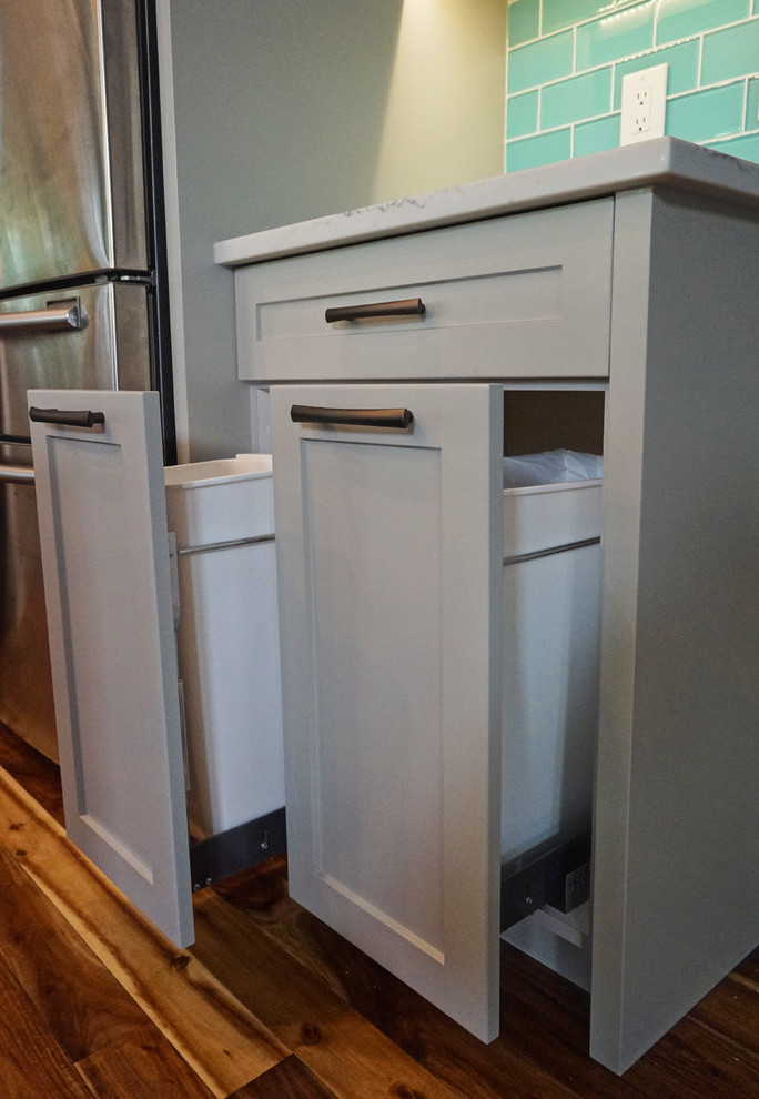 Mid-sized transitional l-shaped medium tone wood floor and brown floor kitchen photo in Calgary with an undermount sink, shaker cabinets, gray cabinets, quartz countertops, blue backsplash, ceramic backsplash, stainless steel appliances and an island