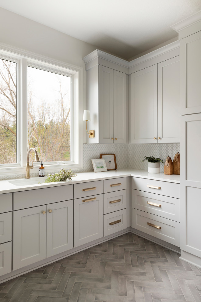 Inspiration for a large transitional utility room in Minneapolis with an utility sink, beaded inset cabinets, grey cabinets, quartzite benchtops, white splashback, porcelain splashback, white walls, porcelain floors, a stacked washer and dryer, grey floor and white benchtop.