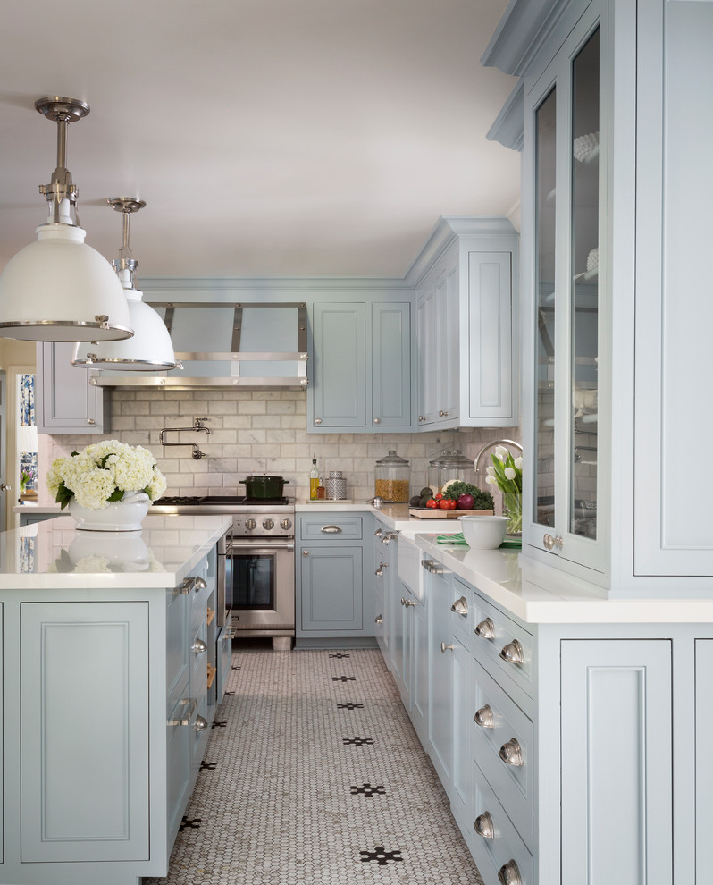 Photo of a transitional l-shaped eat-in kitchen in Little Rock with a farmhouse sink, recessed-panel cabinets, blue cabinets, solid surface benchtops, white splashback, marble splashback, stainless steel appliances, ceramic floors, with island, white floor and white benchtop.