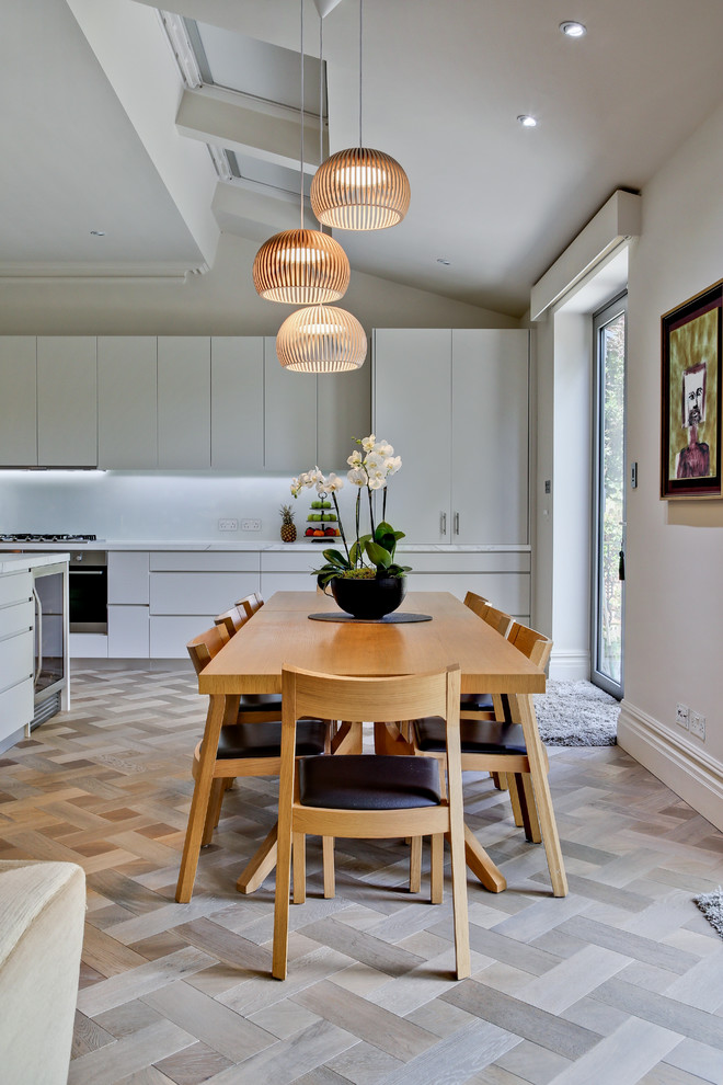 This is an example of a contemporary dining room in London with white walls and light hardwood floors.