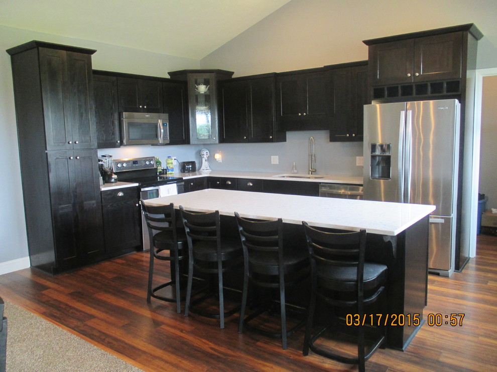 Country l-shaped eat-in kitchen in Louisville with a double-bowl sink, recessed-panel cabinets, dark wood cabinets, quartz benchtops, stainless steel appliances, medium hardwood floors and with island.