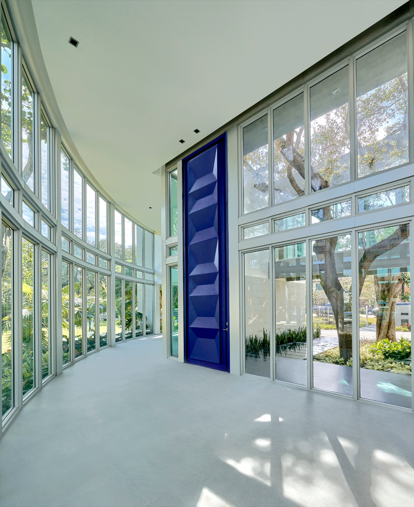 Large modern front door in Miami with limestone floors, a pivot front door and a blue front door.