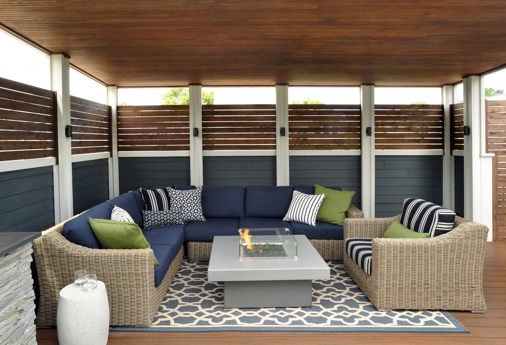 Photo of a large beach style backyard deck in Chicago with a fire feature and a roof extension.